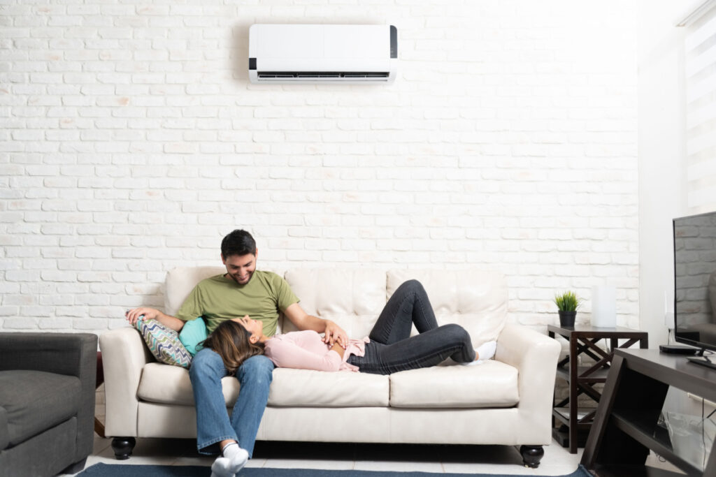 Couple enjoying their new mini split system while relaxing on the couch under the indoor unit