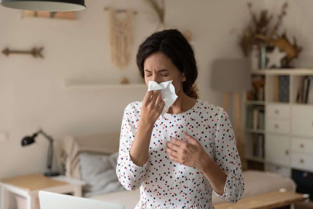 woman sneezing into a tissue in her bedroom due to poor air quality