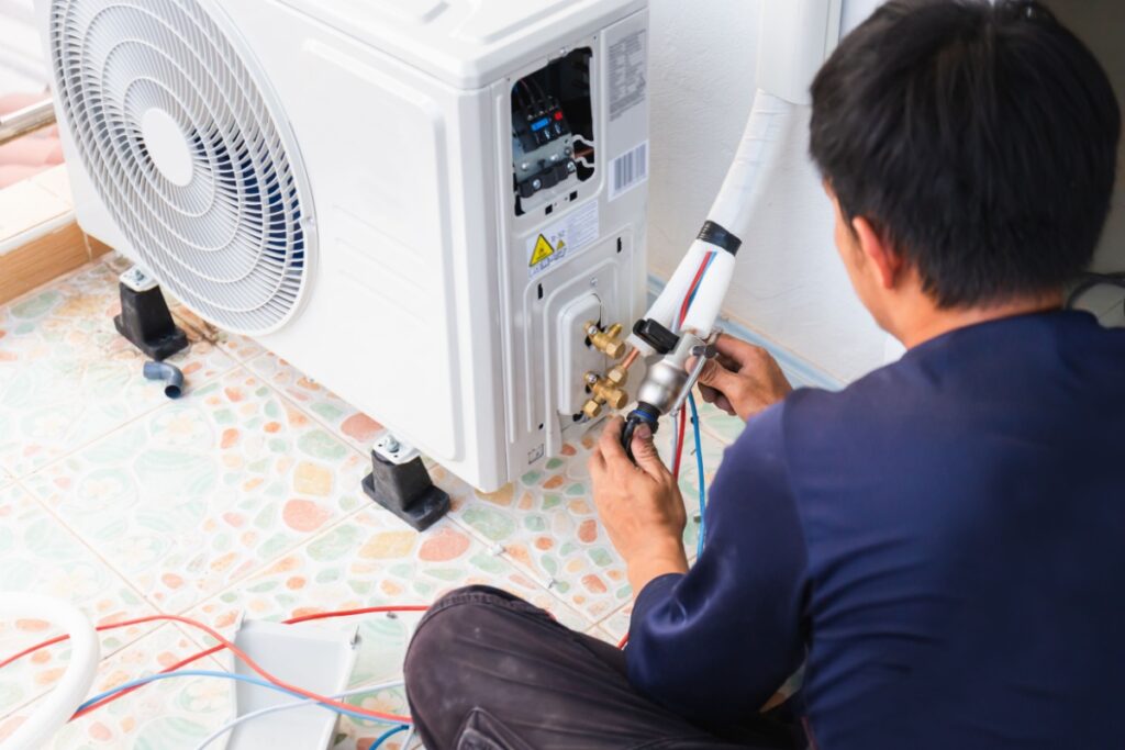 a male HVAC technician installing a new heat pump air conditioner unit